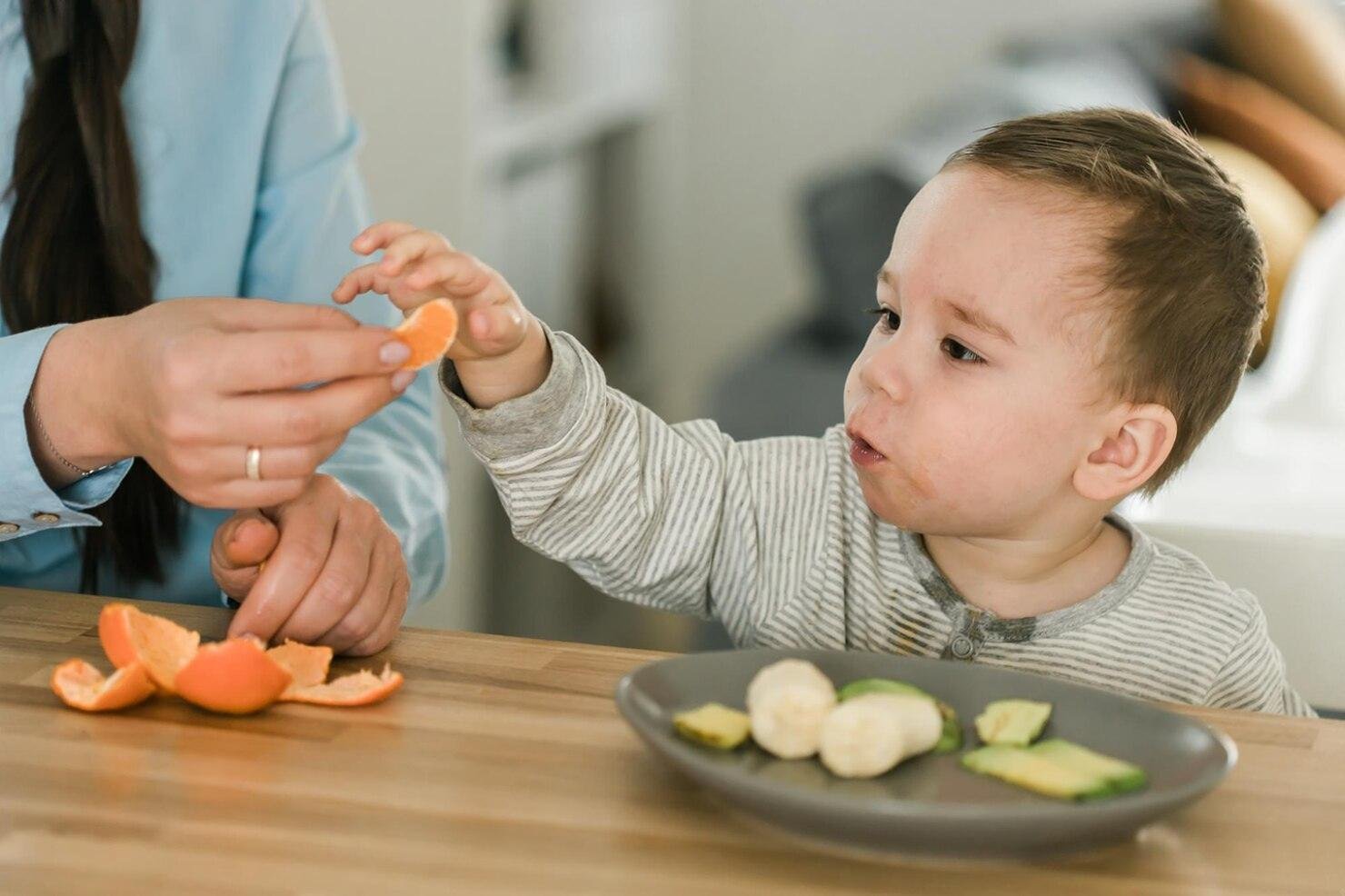 Calm, baby sitting and eating fruit in kitchen